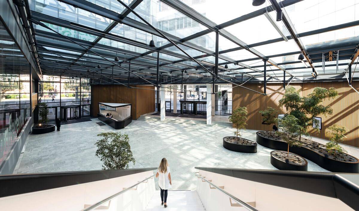 Weitläufiges Atrium mit Glasdach, modernen Pflanzen und viel natürlichem Licht, das eine offene Atmosphäre schafft.