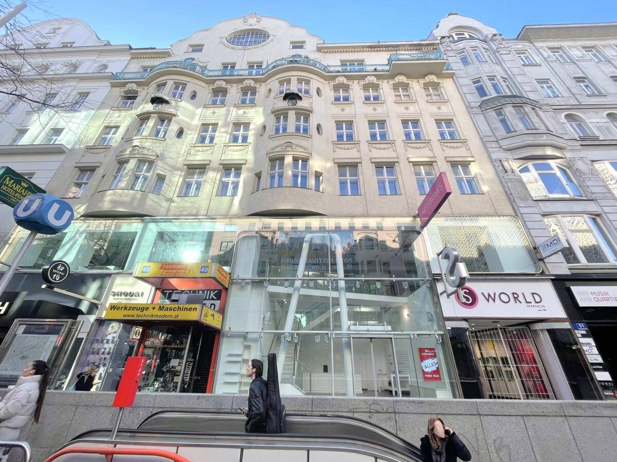 Historisches Gebäude mit moderner Glasfassade im Erdgeschoss, umgeben von anderen Geschäftsgebäuden.