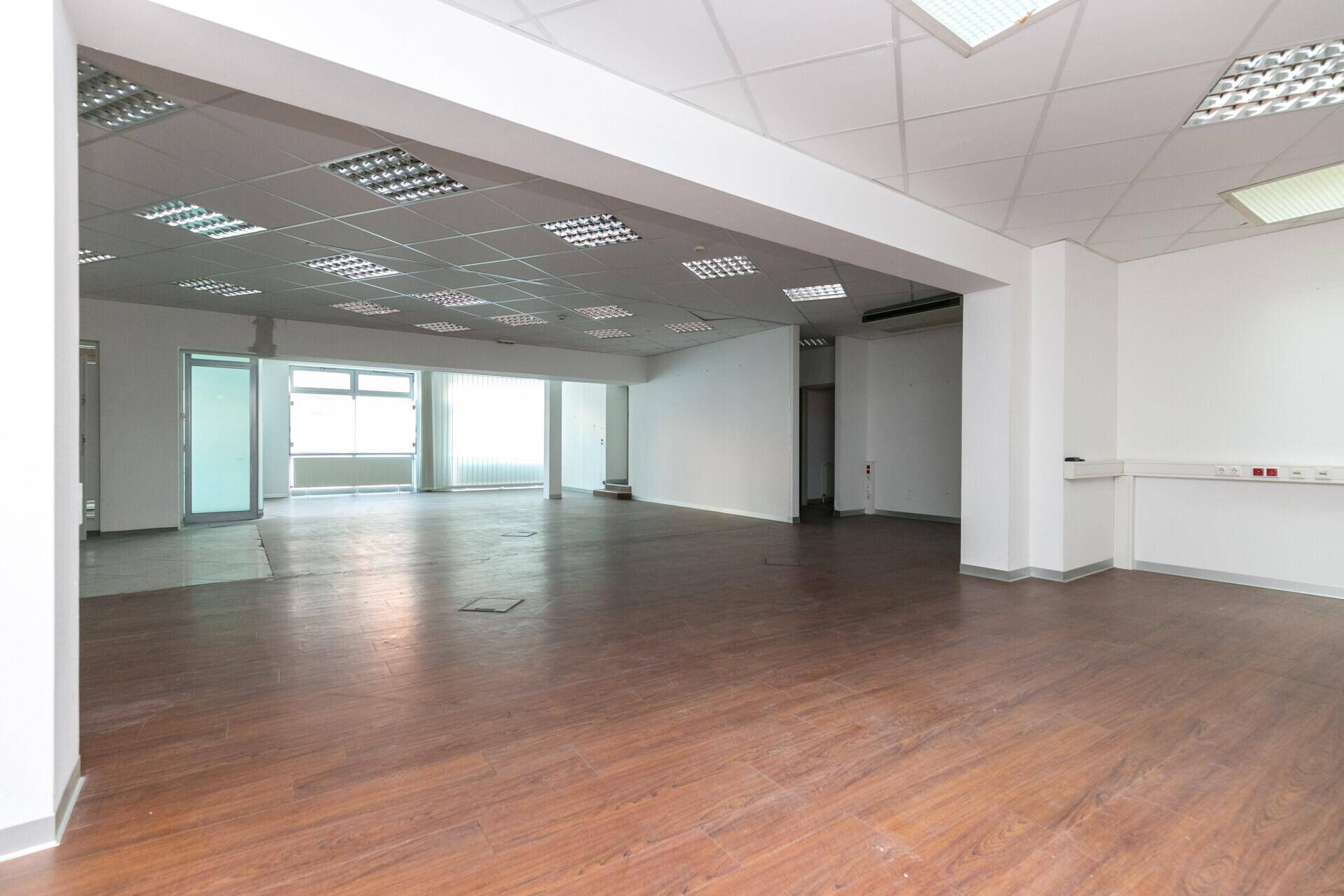 Heller, offener Bürobereich mit Laminatboden und weißen Wänden, ideal für flexible Nutzung.