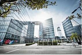 Moderne Bürogebäude mit Glasfassaden und markanter Architektur unter strahlendem Sonnenschein.
