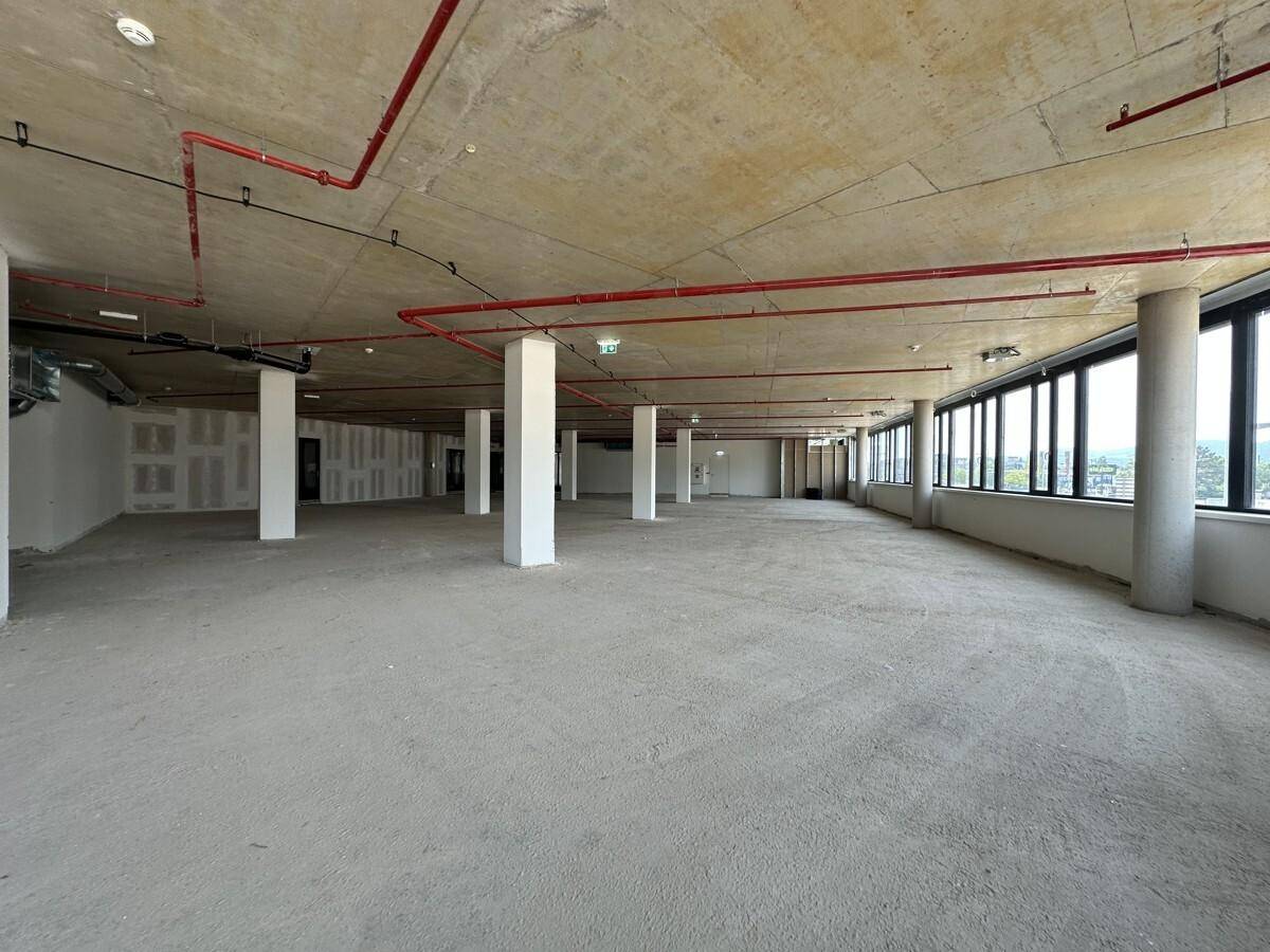Geräumiger Gewerberaum im Rohbau mit mehreren Säulen und sichtbaren Deckeninstallationen.
