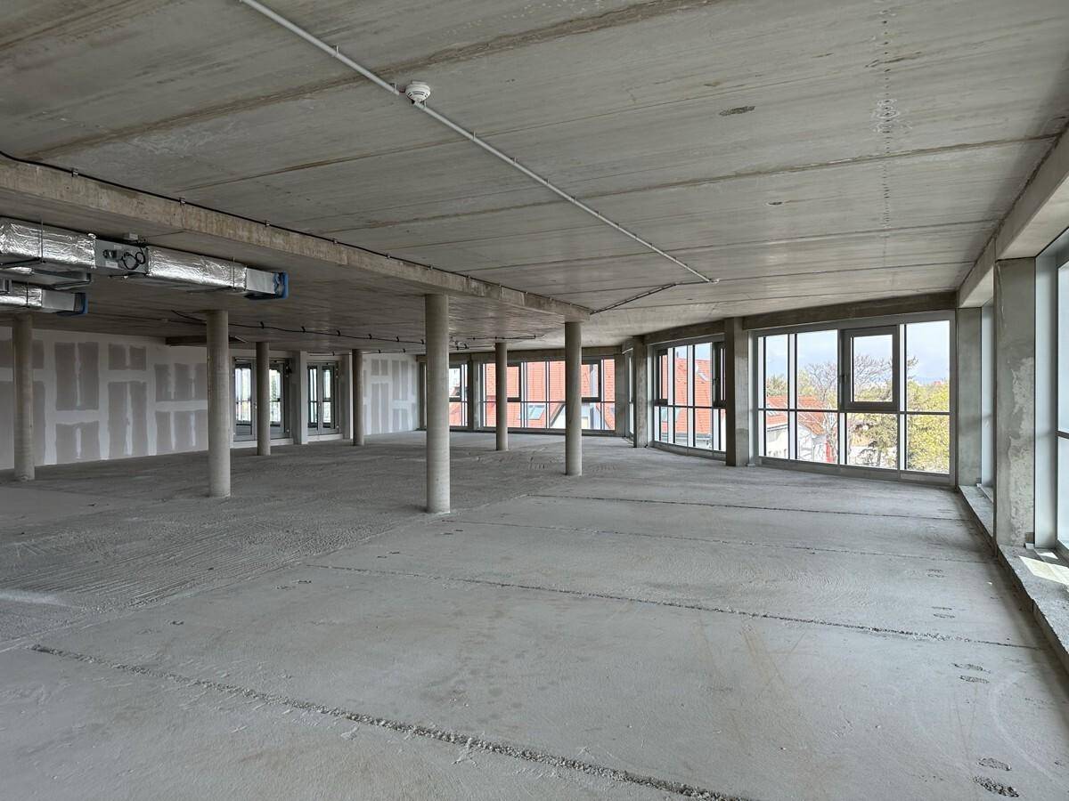 Großer, offener Büroraum im Rohbau mit Betonboden und Betondecke, bereit für den Innenausbau.