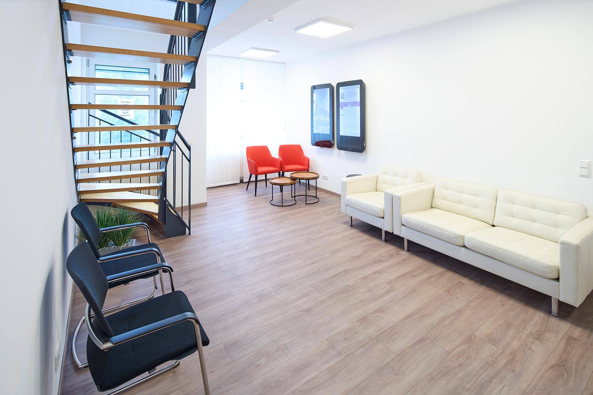 Moderner Wartebereich mit bequemen Sofas, Sesseln und einem Holzboden, ideal für Besucher oder kurze Pausen.