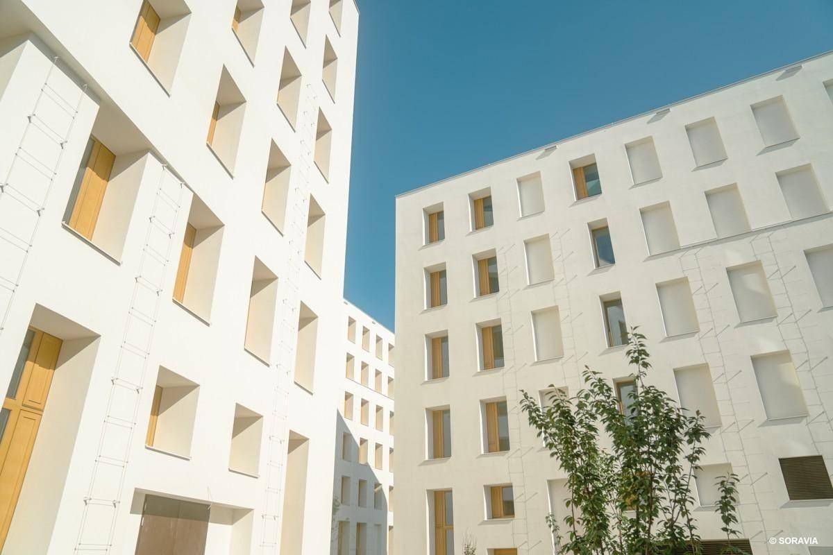 Moderne weiße Fassaden mit vielen Fenstern und klarem Himmel im Hintergrund.