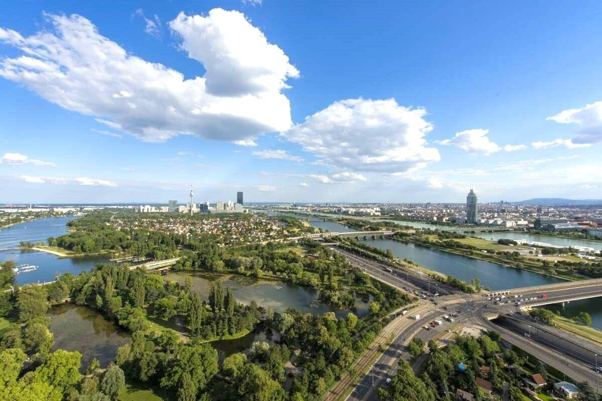 Weitläufige Luftaufnahme einer Stadtlandschaft mit Flüssen, Brücken und viel Grün.