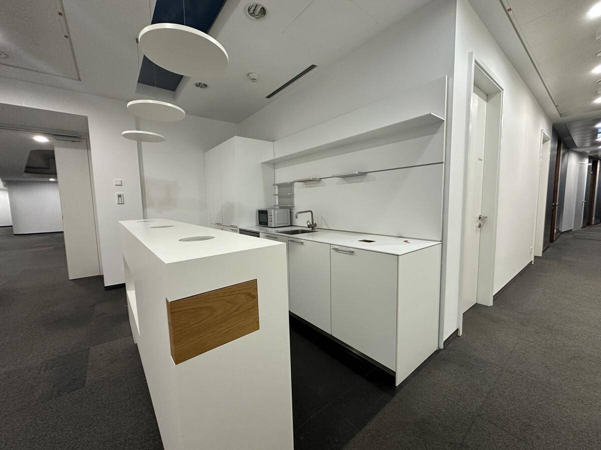 Helle Teeküche mit weißer Theke, integrierten Geräten und modernem Design, bietet Funktionalität und Stil.