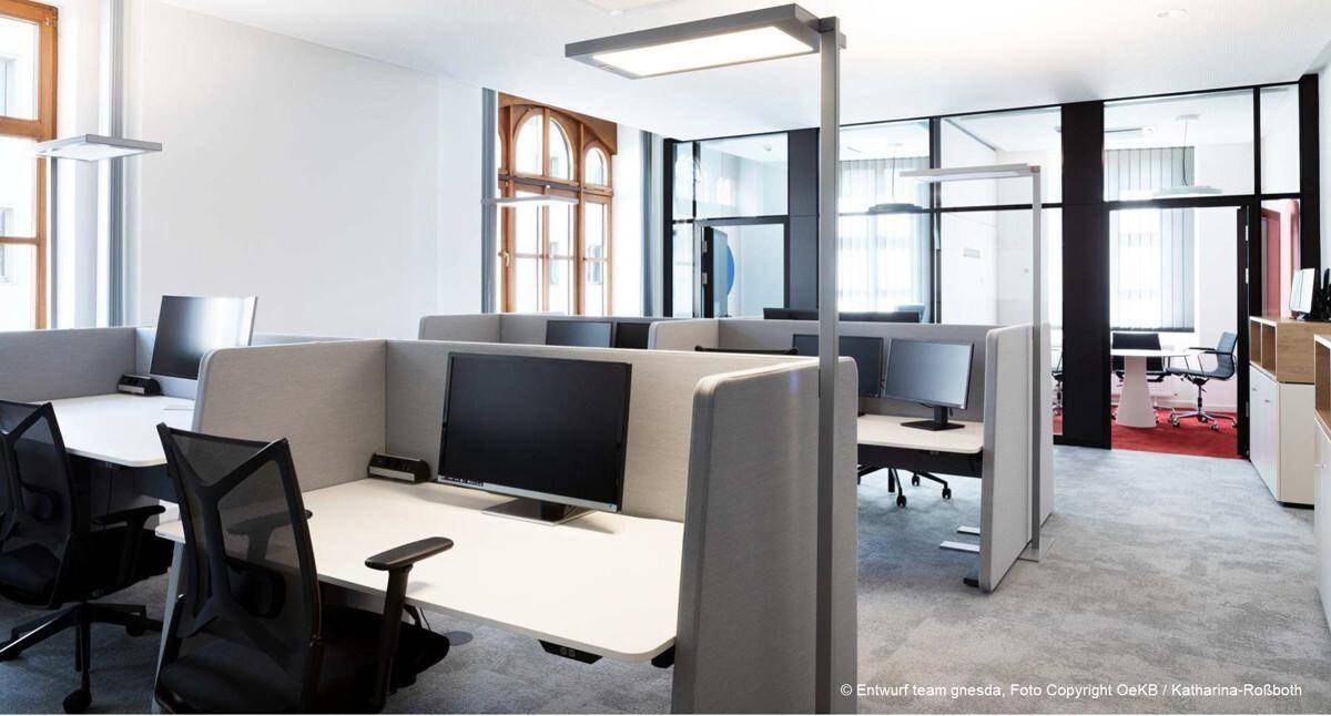 Moderner Großraumbüro mit ergonomischen Arbeitsplätzen, Trennwänden und viel Tageslicht.