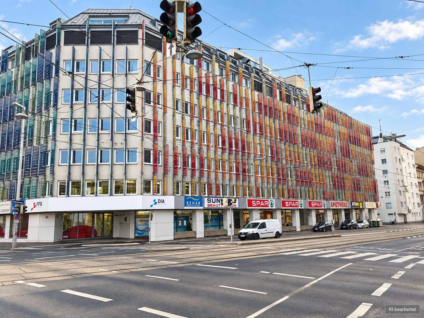 Modernes Bürogebäude an einer städtischen Kreuzung mit farbenfroher Fassadengestaltung und Einzelhandelsflächen im Erdgeschoss.