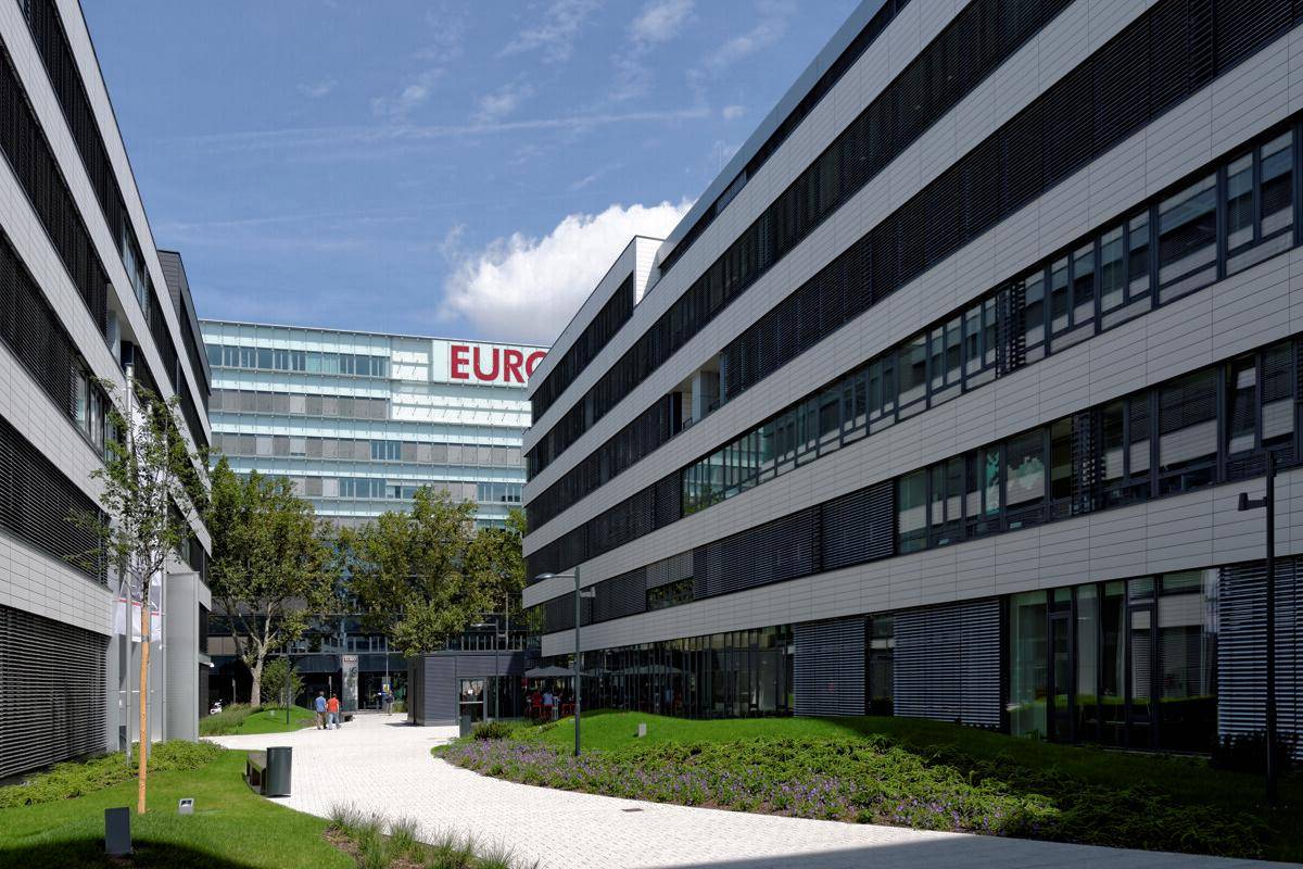 Moderne Bürogebäude mit markanter Beschriftung und gepflegten Außenbereichen, die zum Verweilen einladen.