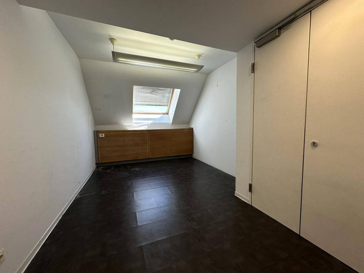 Dachgeschossraum mit dunklem Boden, Dachfenster und Einbauschränken, ideal als Büro.