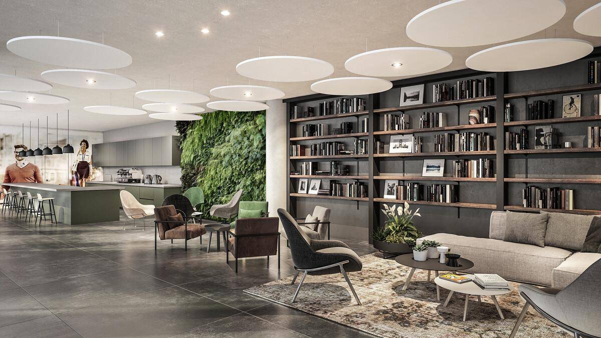 Geräumiger Loungebereich mit Bücherregal, Sitzgelegenheiten und offener Küchenzeile im Hintergrund.