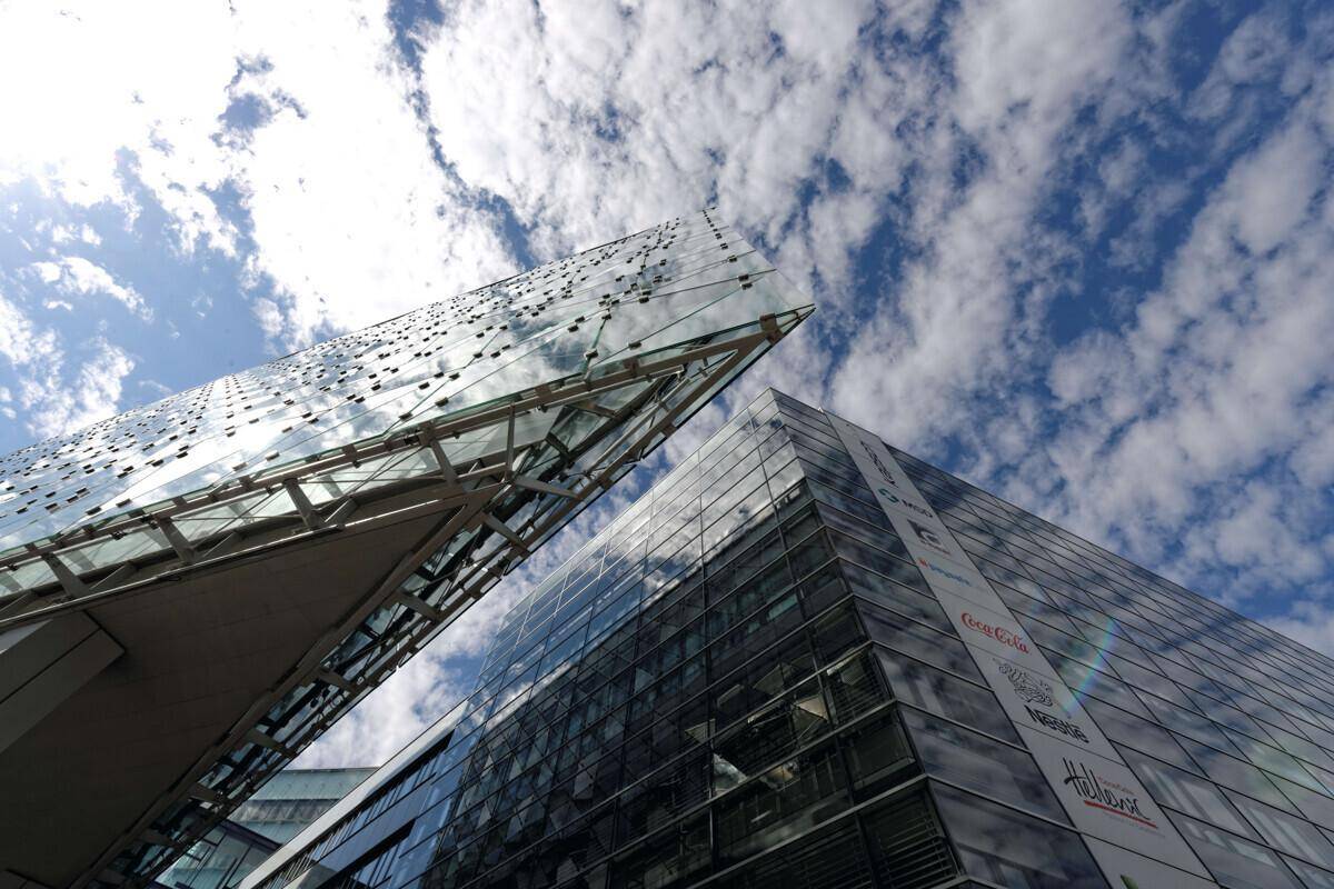 Beeindruckende Glasfassade eines modernen Bürogebäudes unter einem blauen Himmel mit weißen Wolken.