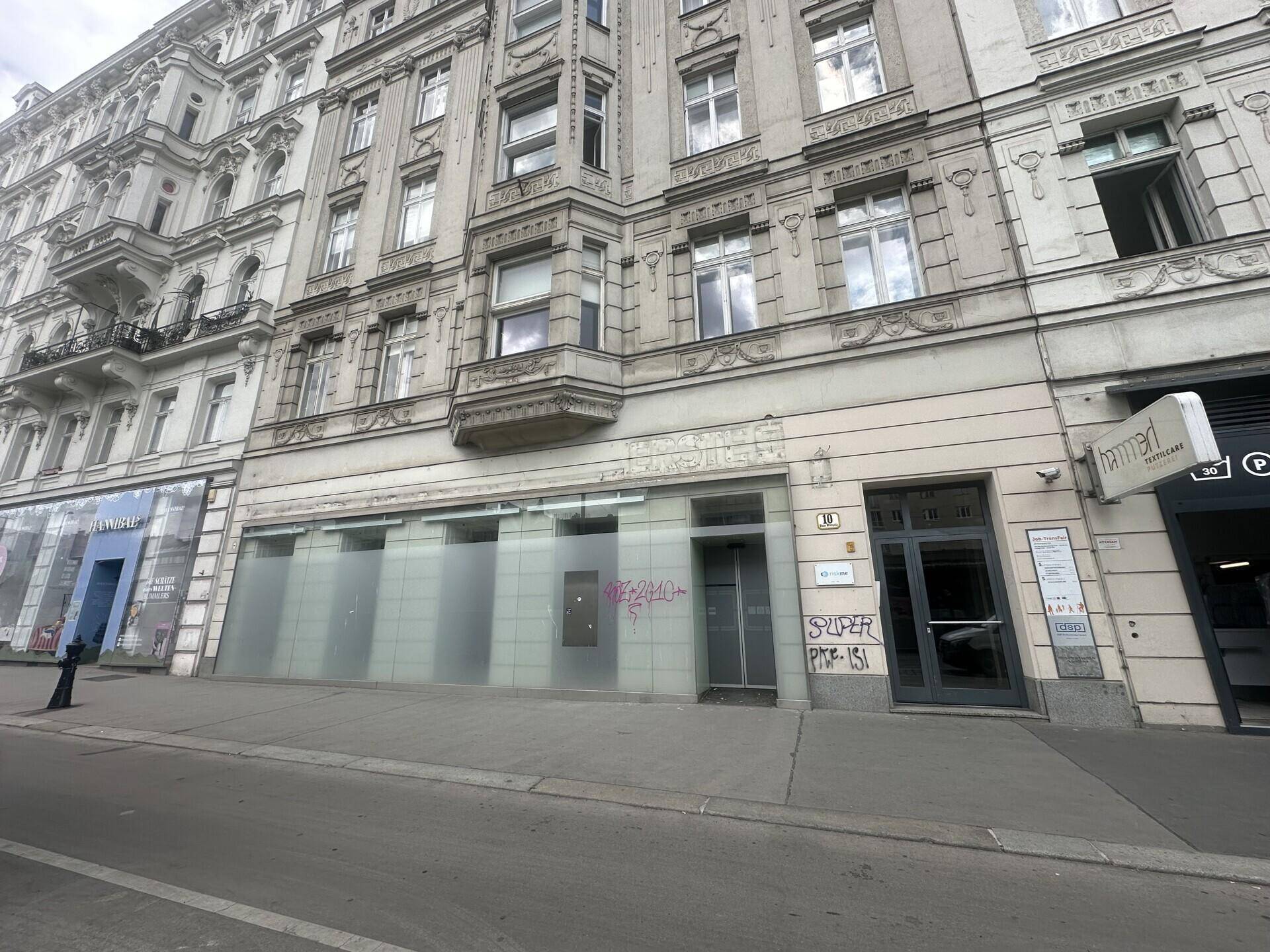 Nahaufnahme der historischen Gebäudefassade mit Ladengeschäft im Erdgeschoss und Details der Architektur.