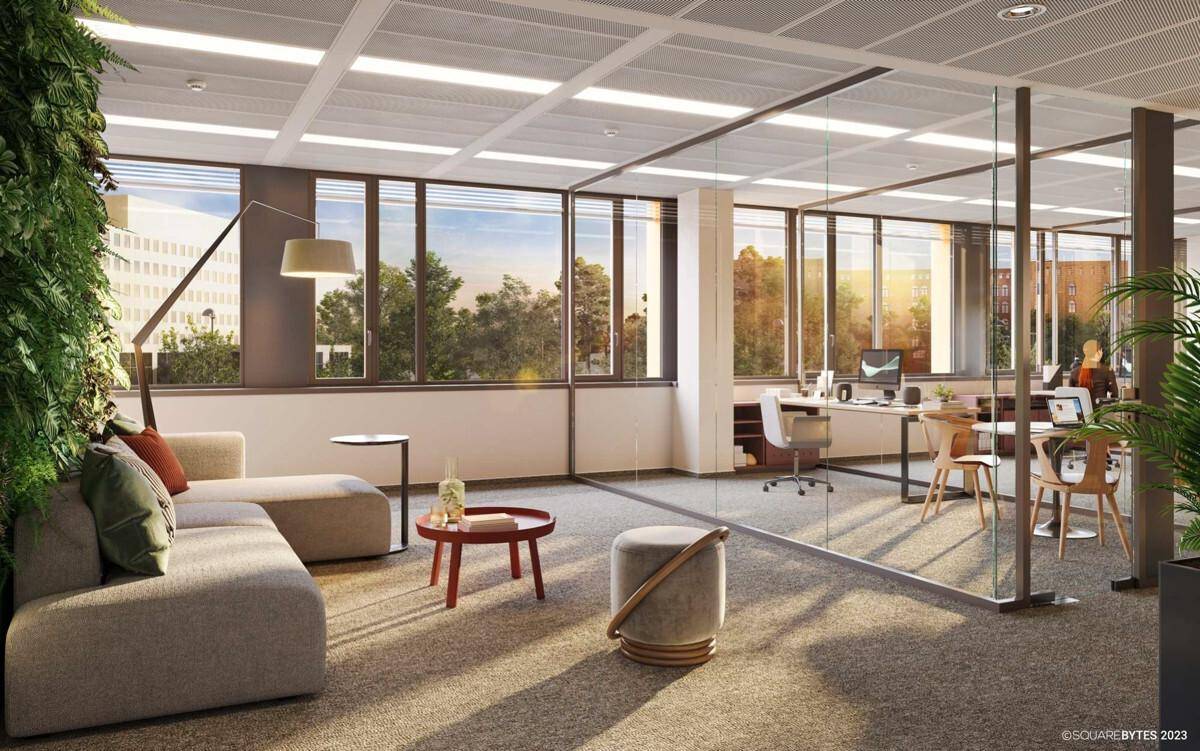 Heller Loungebereich im Büro mit bequemer Couch, großen Fenstern und viel Tageslicht.