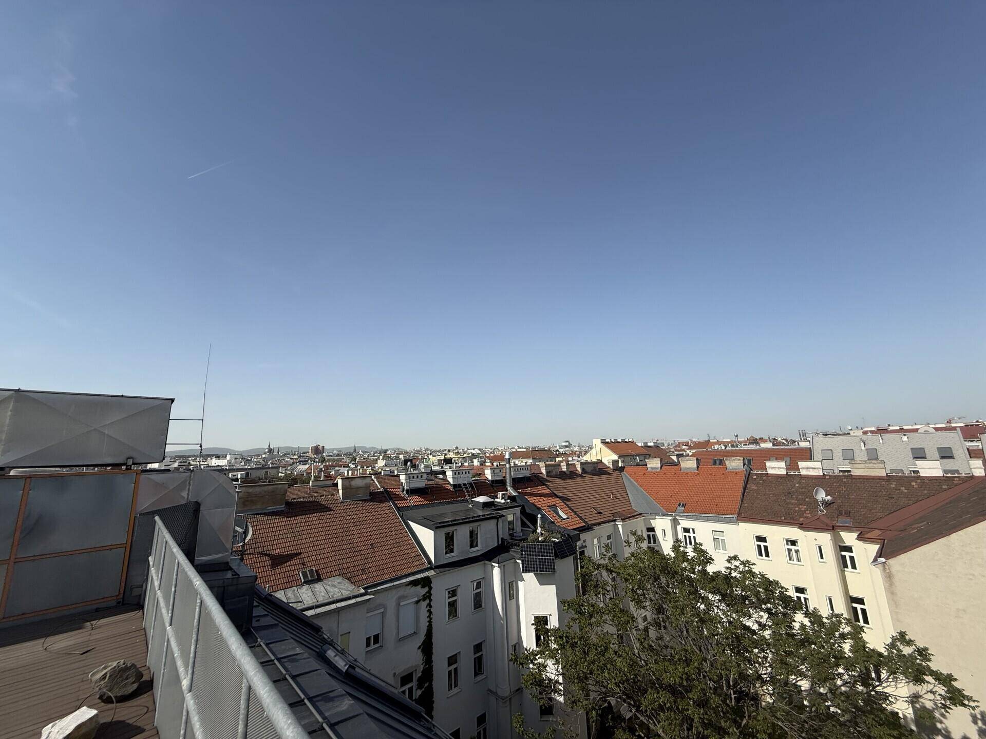 Weitläufiger Blick über die Dächer der Stadt unter einem klaren blauen Himmel.