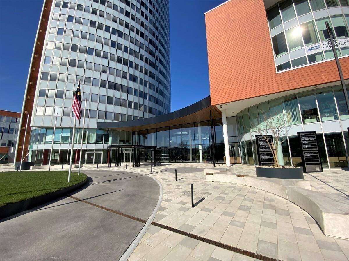 Moderne Bürogebäude mit Glasfassaden und einem gepflegten Eingangsbereich unter blauem Himmel.