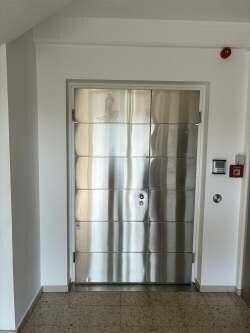 Ein großer, moderner Aufzug mit glänzenden Metalltüren in einem hellen Flurbereich.
