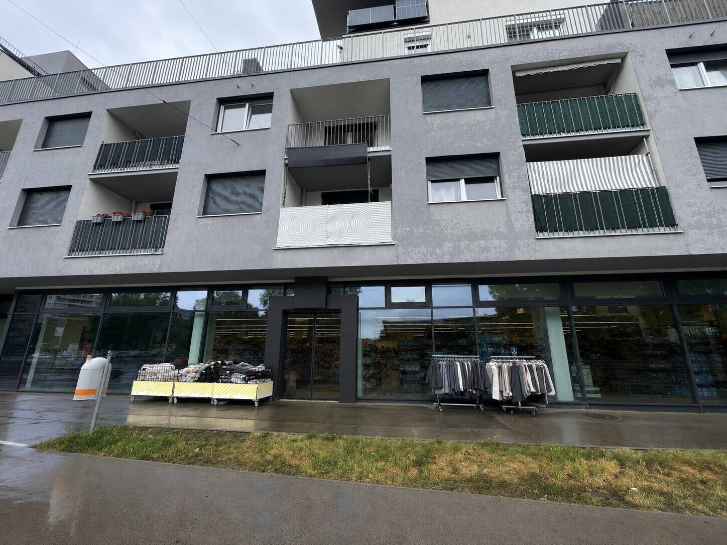 Nahaufnahme der modernen Fassade eines Gebäudes mit Geschäften im Erdgeschoss und Wohnungen darüber.