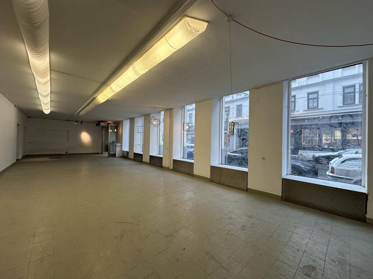 Weitläufiger Gewerberaum mit zahlreichen großen Fenstern zur Straße, die eine helle Atmosphäre schaffen.
