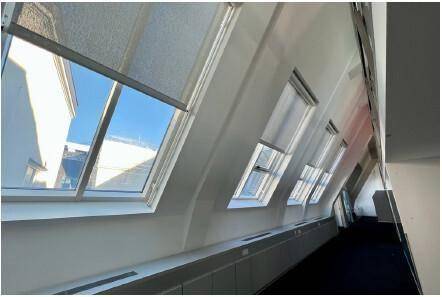Büroraum im Dachgeschoss mit schrägen Wänden und mehreren Dachfenstern für viel Tageslicht.