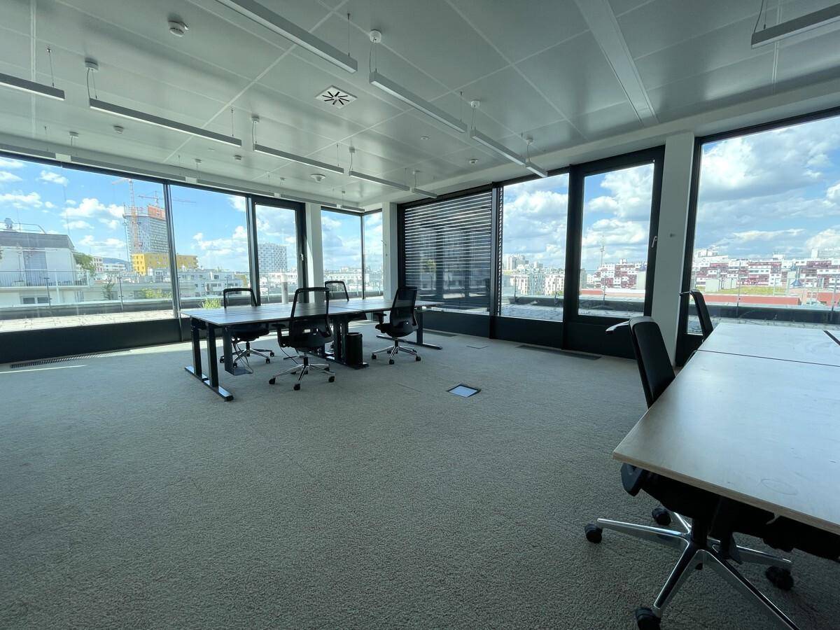 Heller Besprechungsbereich in einem modernen Büro mit Teppichboden und weitem Blick über die Stadt.
