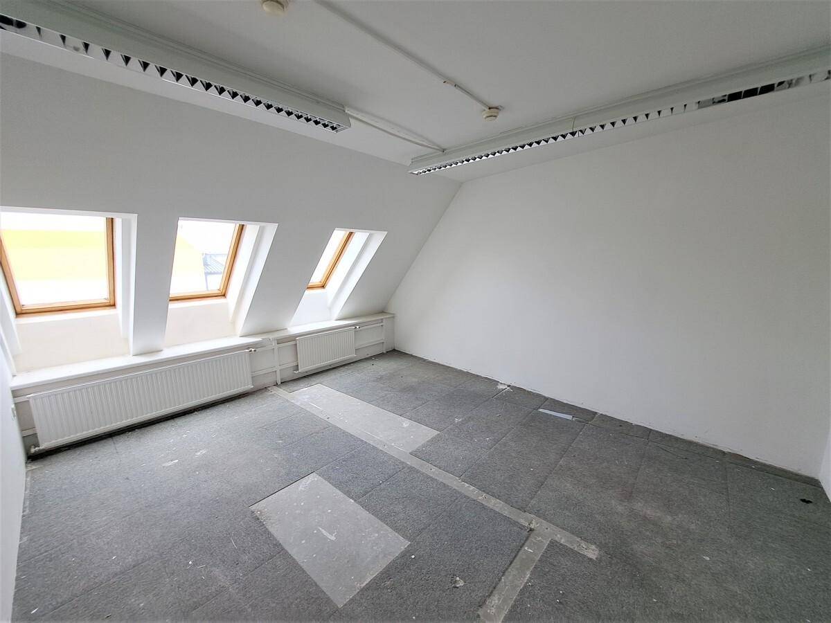 Helles Dachgeschosszimmer mit drei Dachfenstern, Heizkörpern und Teppichboden, ideal als Büro oder Lagerraum.