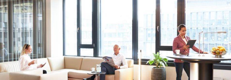 Heller und moderner Loungebereich mit bequemen Sofas, großen Fenstern und Blick auf die Stadt.