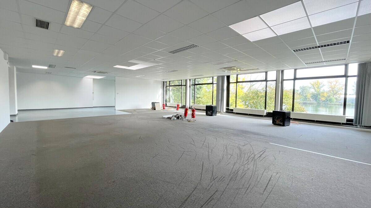 Großer offener Gewerberaum mit Teppich- und Vinylboden, großen Fenstern und Seeblick.