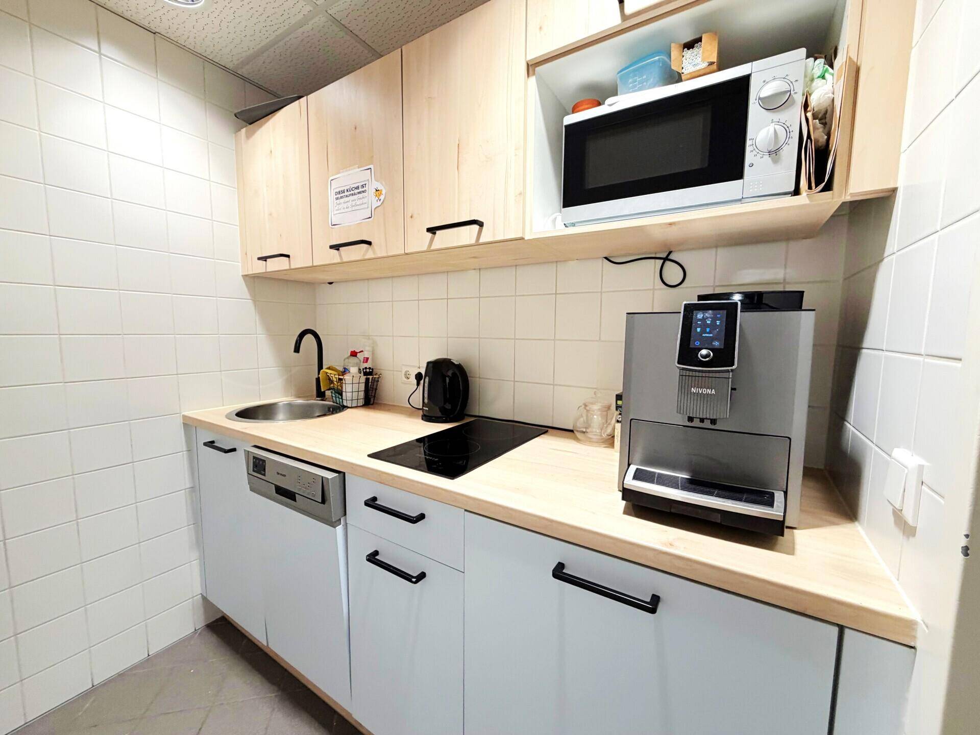 Saubere Gästetoilette mit Urinal, Waschbecken und Handtrockner in funktionalem Design.