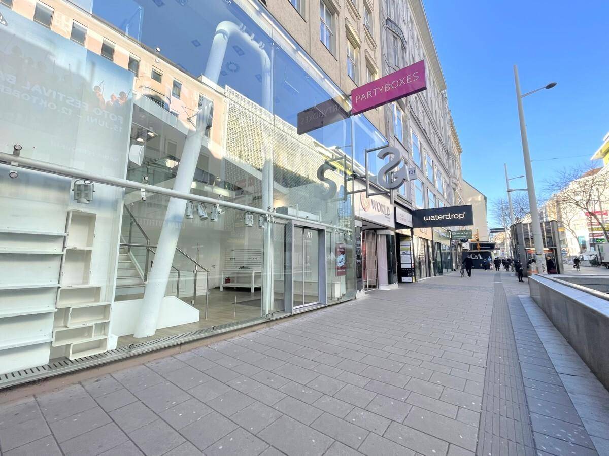 Weitläufige Straßenansicht mit moderner Glasfassade des Geschäftsgebäudes und Passanten auf dem Gehweg.