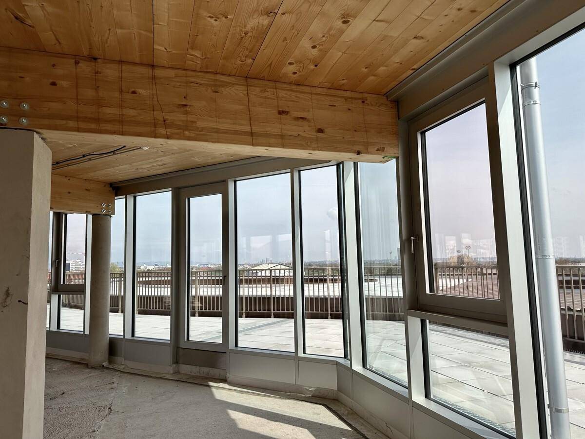 Detailansicht der großen Fensterfront in einem Büroraum im Rohbau mit Blick auf die Umgebung.