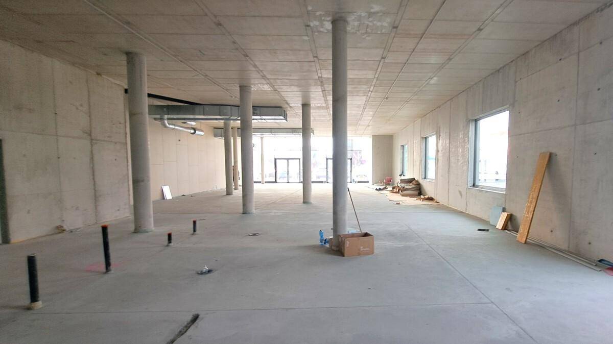 Weiterer Blick in den Rohbau des Geschäftsraums mit vielen Betonsäulen und einem glatten Betonboden.