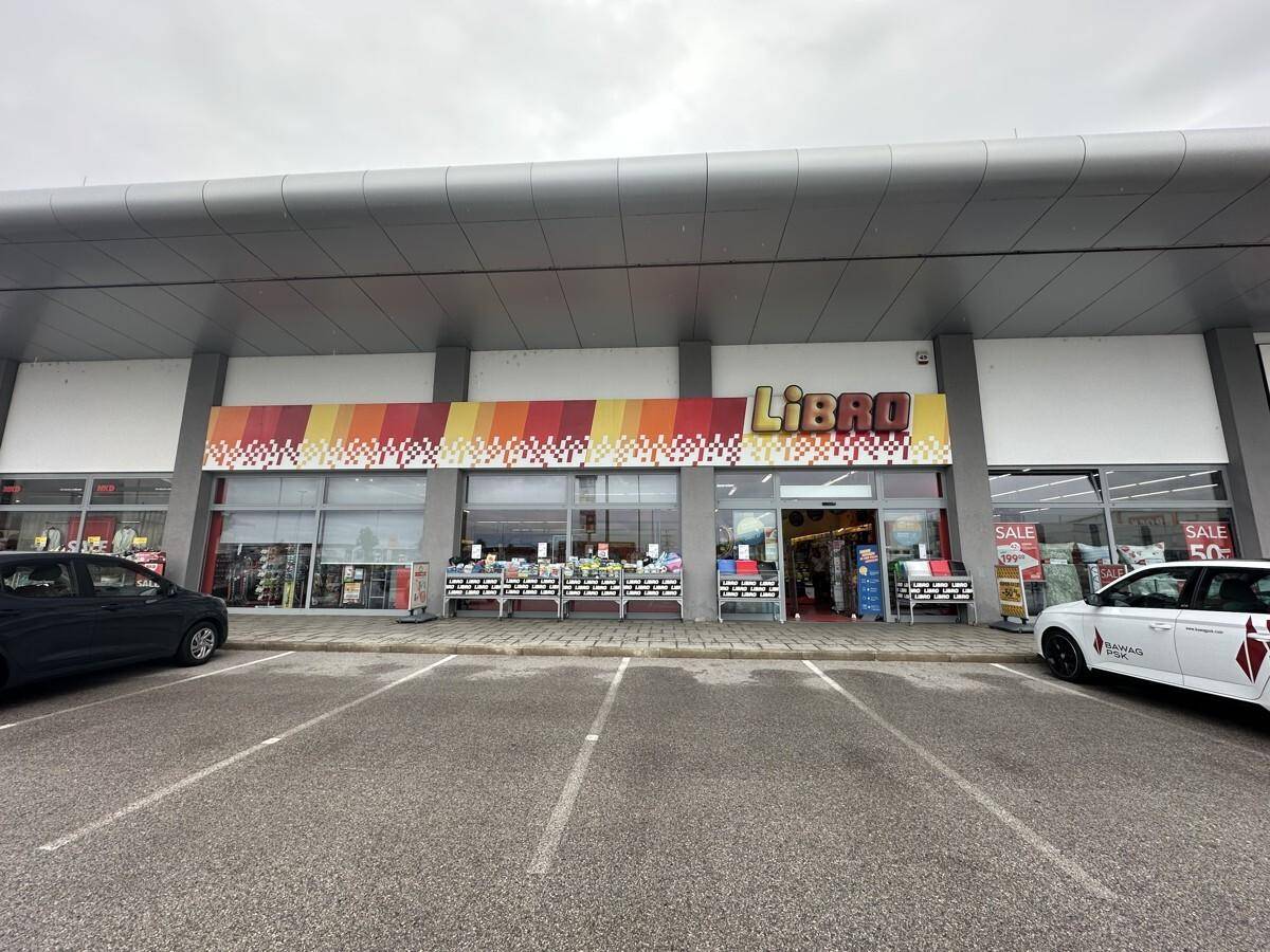 Weitwinkelaufnahme der Geschäftsfassade von Libro mit davorliegendem, leerem Parkplatz unter grauem Himmel.