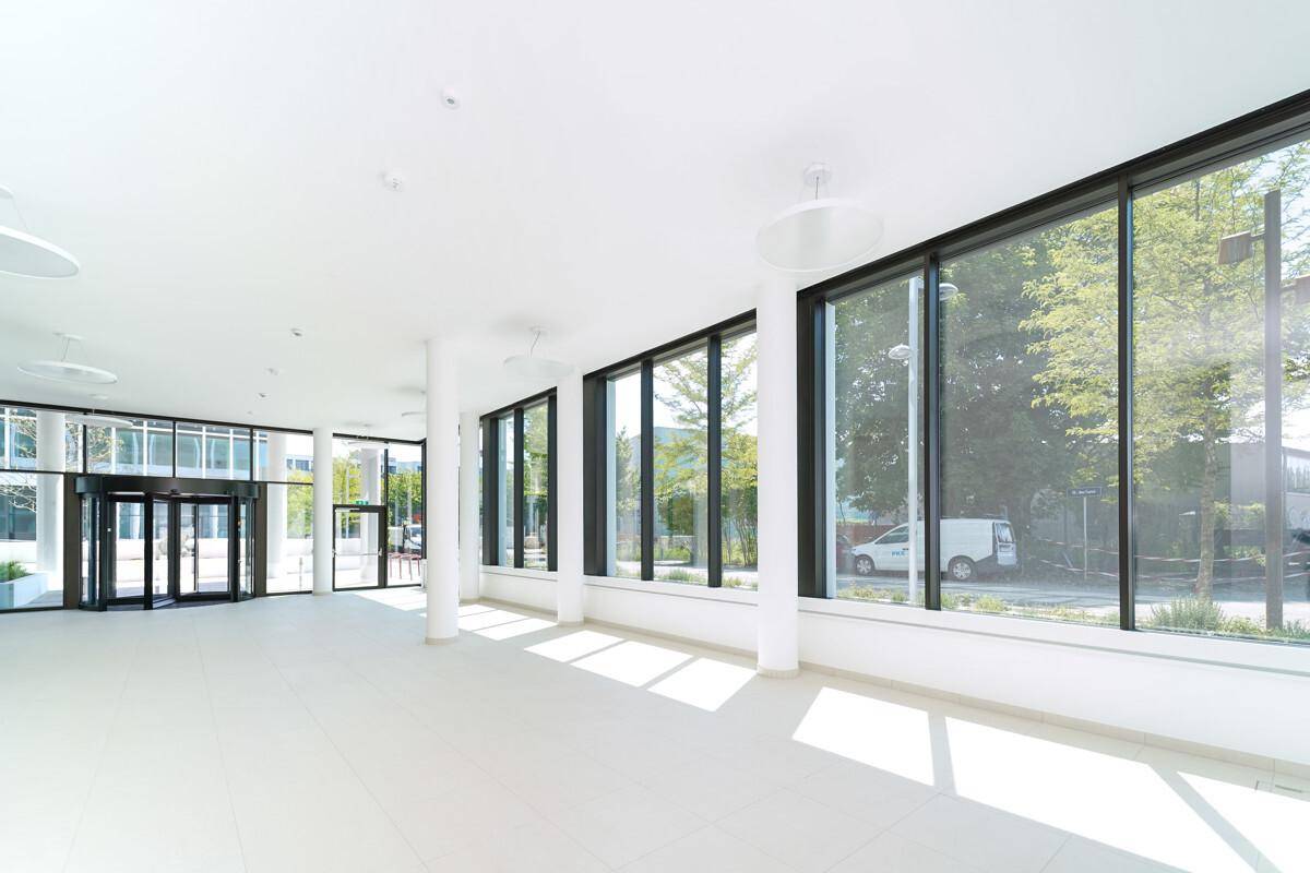 Heller Eingangsbereich mit großen Fenstern, die viel Tageslicht hereinlassen und einen Blick auf die Straße bieten.