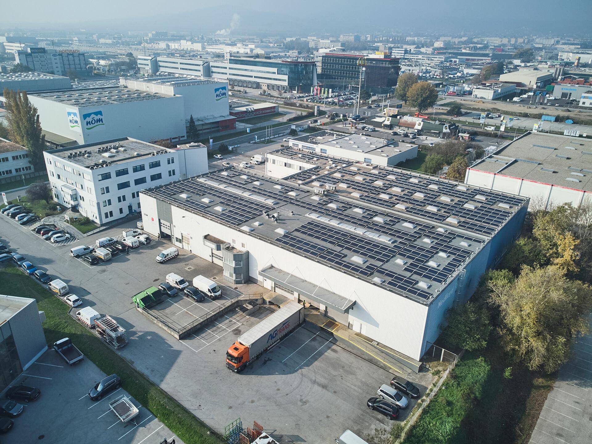 Eine weitere Luftaufnahme des Gewerbegebiets mit großen Hallen, Laderampen und vielen Fahrzeugen.