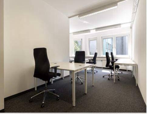 Funktionales Büro mit Teppichboden, großen Fenstern und mehreren Schreibtischen für effiziente Arbeitsplätze.