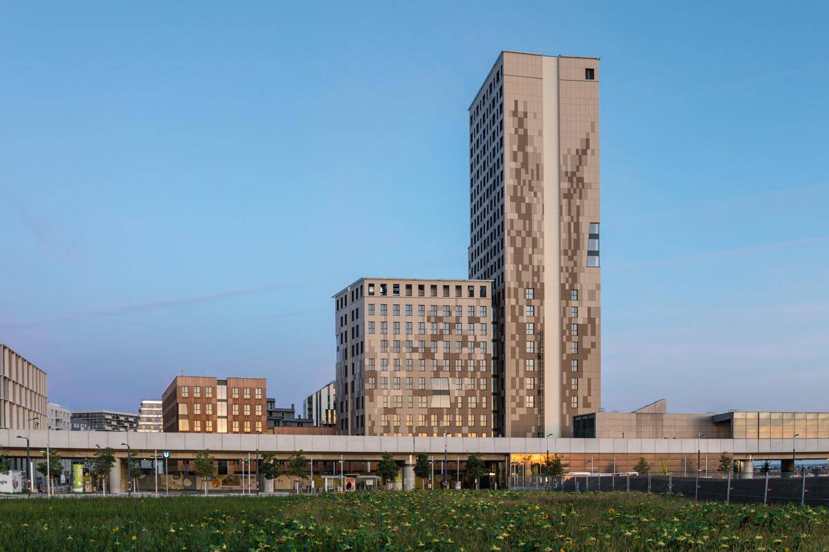 Moderne Hochhäuser mit markanter Fassadengestaltung und weitem Blick über eine Grünfläche bei Dämmerung.