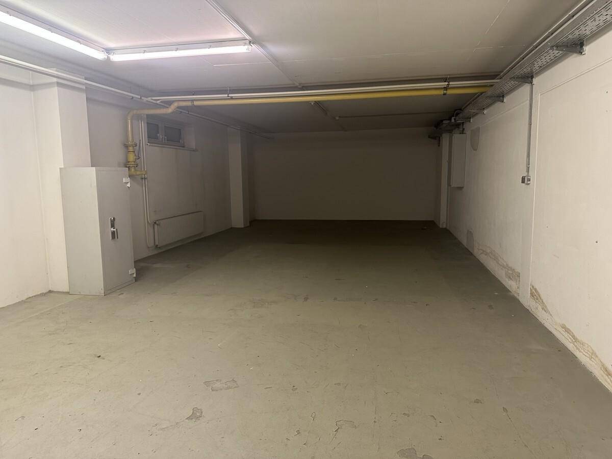 Großer Kellerraum mit Betonboden, Heizkörper und einem Sicherheitsschrank an der Wand, vielseitig nutzbar.