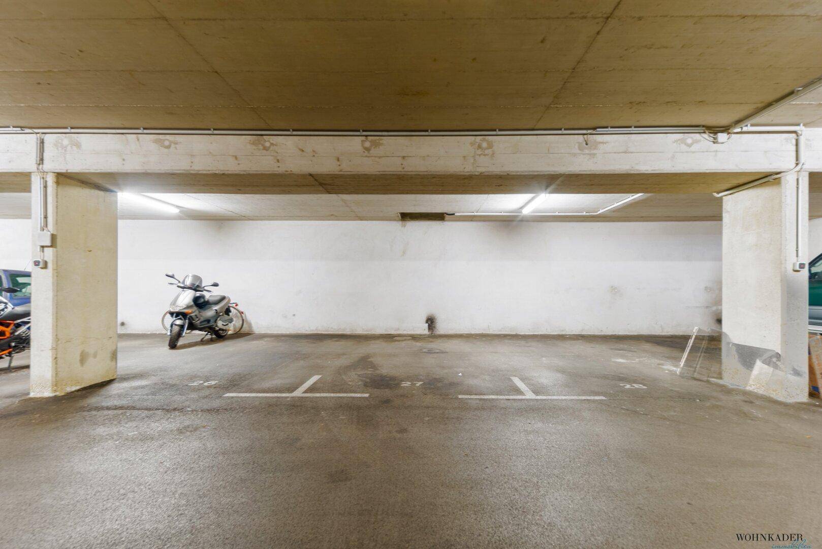 Tiefgarage mit ausreichend Stellplätzen und Beleuchtung für Fahrzeuge.