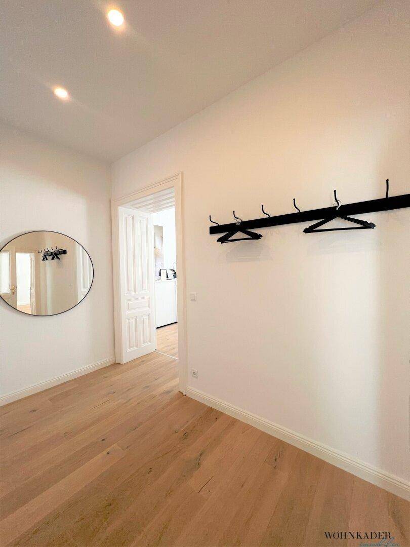 Funktionaler Flur mit Rundspiegel und Wandgarderobe, bietet Platz für Jacken und Mäntel.