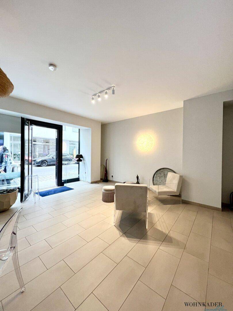 Heller Eingangsbereich des Büros mit modernen Fliesen, einem Sitzbereich und Blick zur Straße.