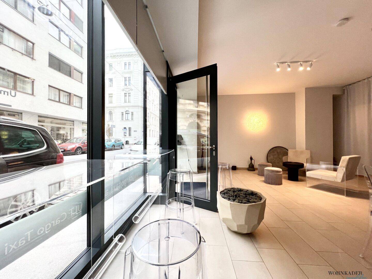 Blick vom Fensterbereich in den Büroraum mit transparenten Hockern und einem dekorativen Pflanzgefäß.