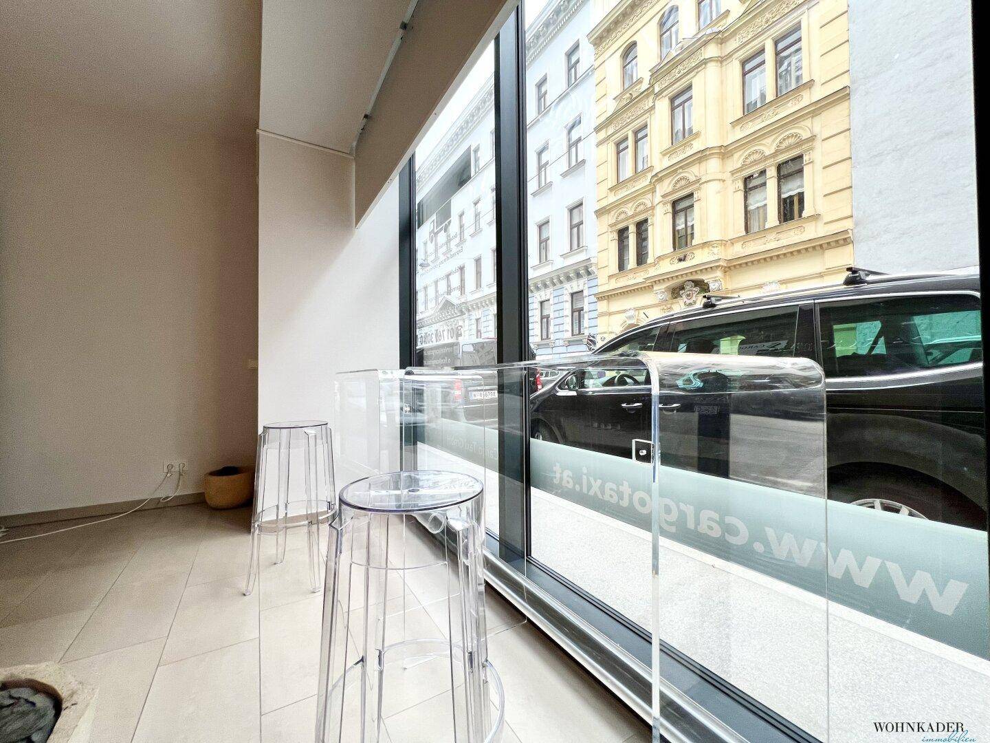 Heller Eingangsbereich des Büros mit modernen Fliesen, einem Sitzbereich und Blick zur Straße.