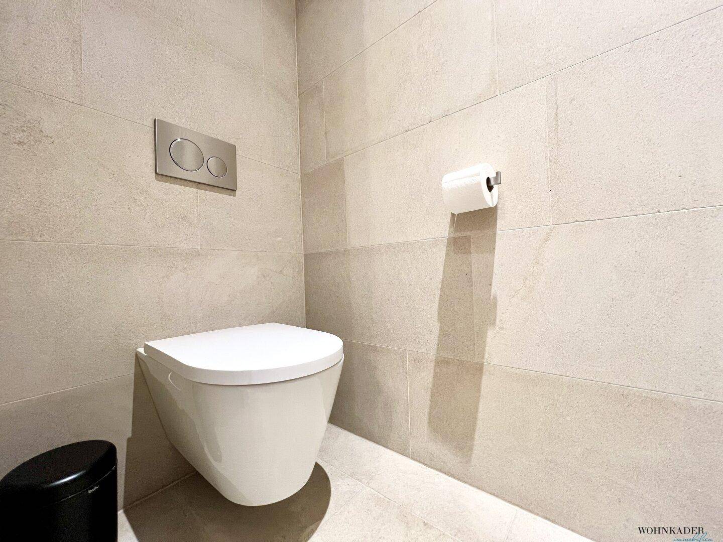 Modernes Gäste-WC mit Waschbecken, Spiegel und indirekter Beleuchtung, in hellen Farbtönen gehalten.