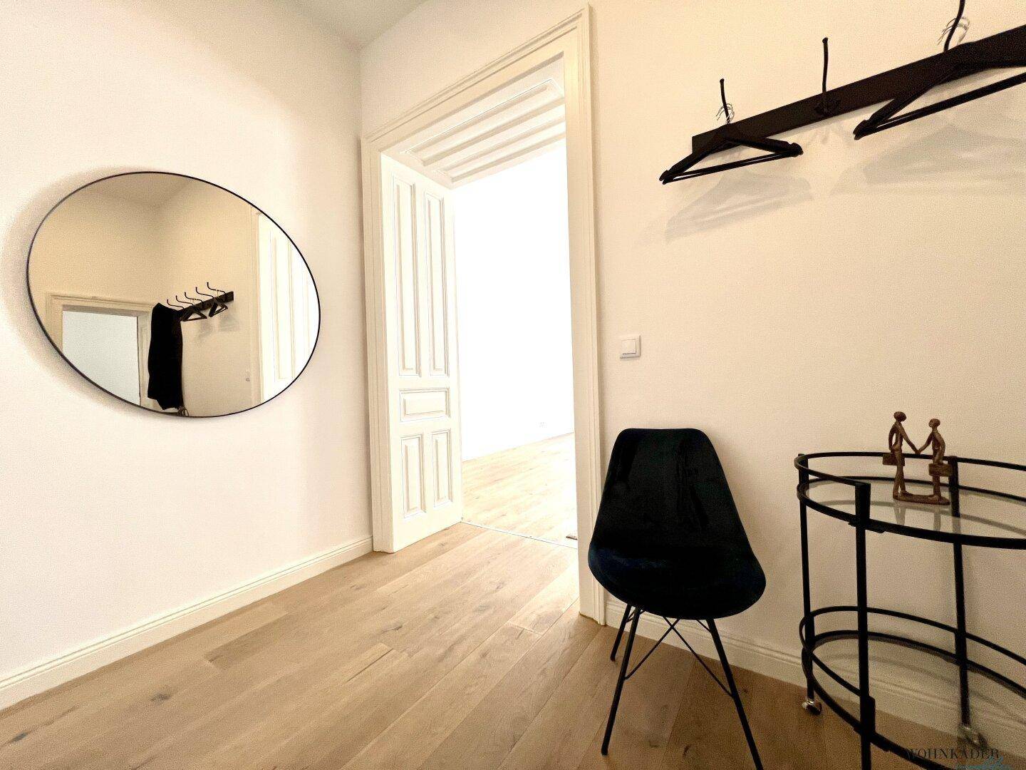 Eingangsbereich mit praktischer Garderobe, kleinem Beistelltisch und einem Stuhl, führt zu weiteren Räumen.