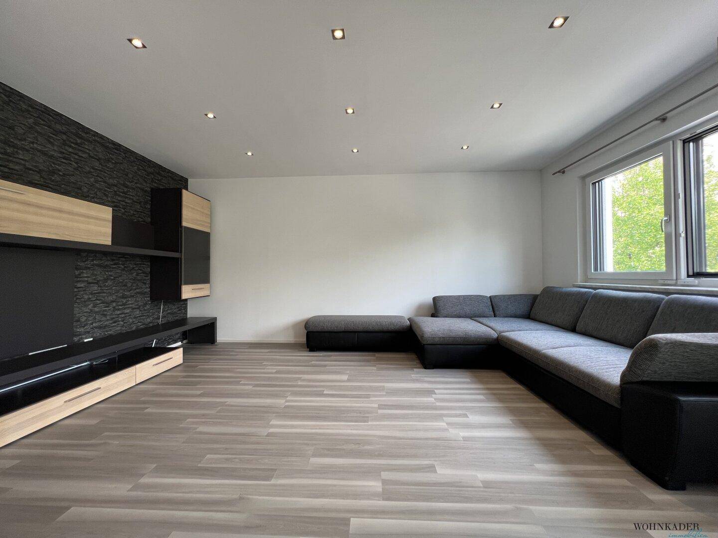 Geräumiges Wohnzimmer mit großem Ecksofa und moderner Medienwand mit Steinakzenten.