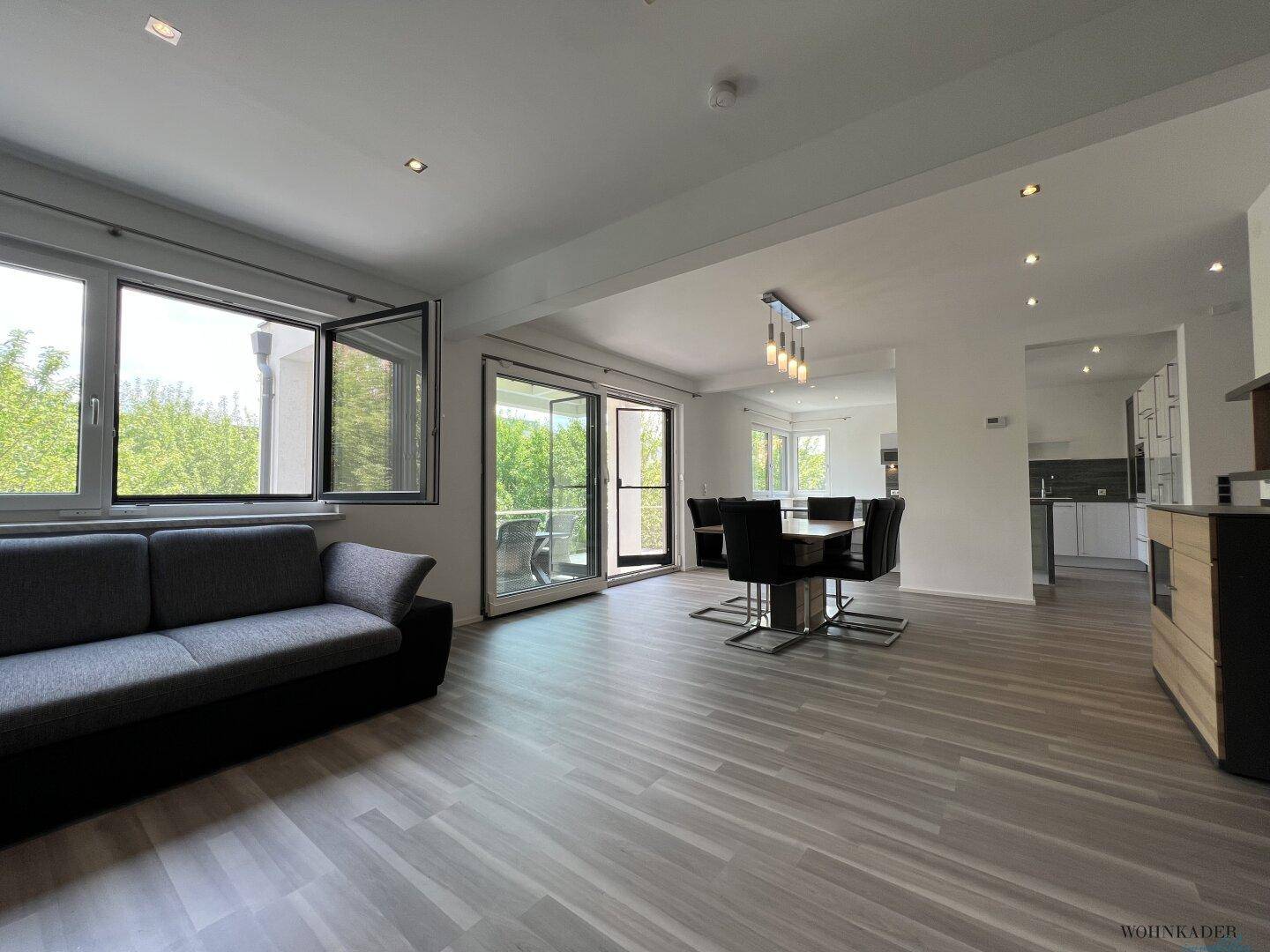 Offener Wohn-Essbereich mit viel Tageslicht, modernem Mobiliar und Zugang zur Terrasse.