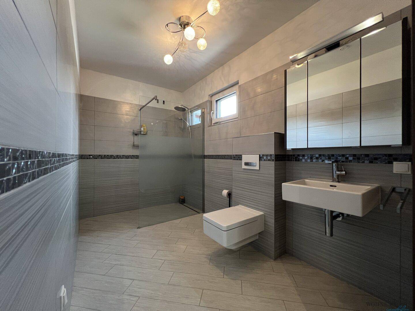 Modernes Badezimmer mit großer begehbarer Dusche, Wand-WC und Einzelwaschbecken.
