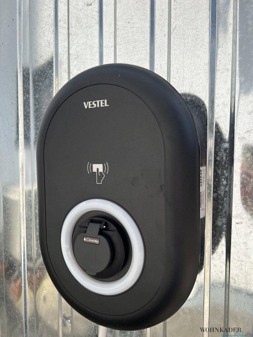 Moderne Ladestation für Elektrofahrzeuge an einer Außenwand, bereit zur Nutzung.