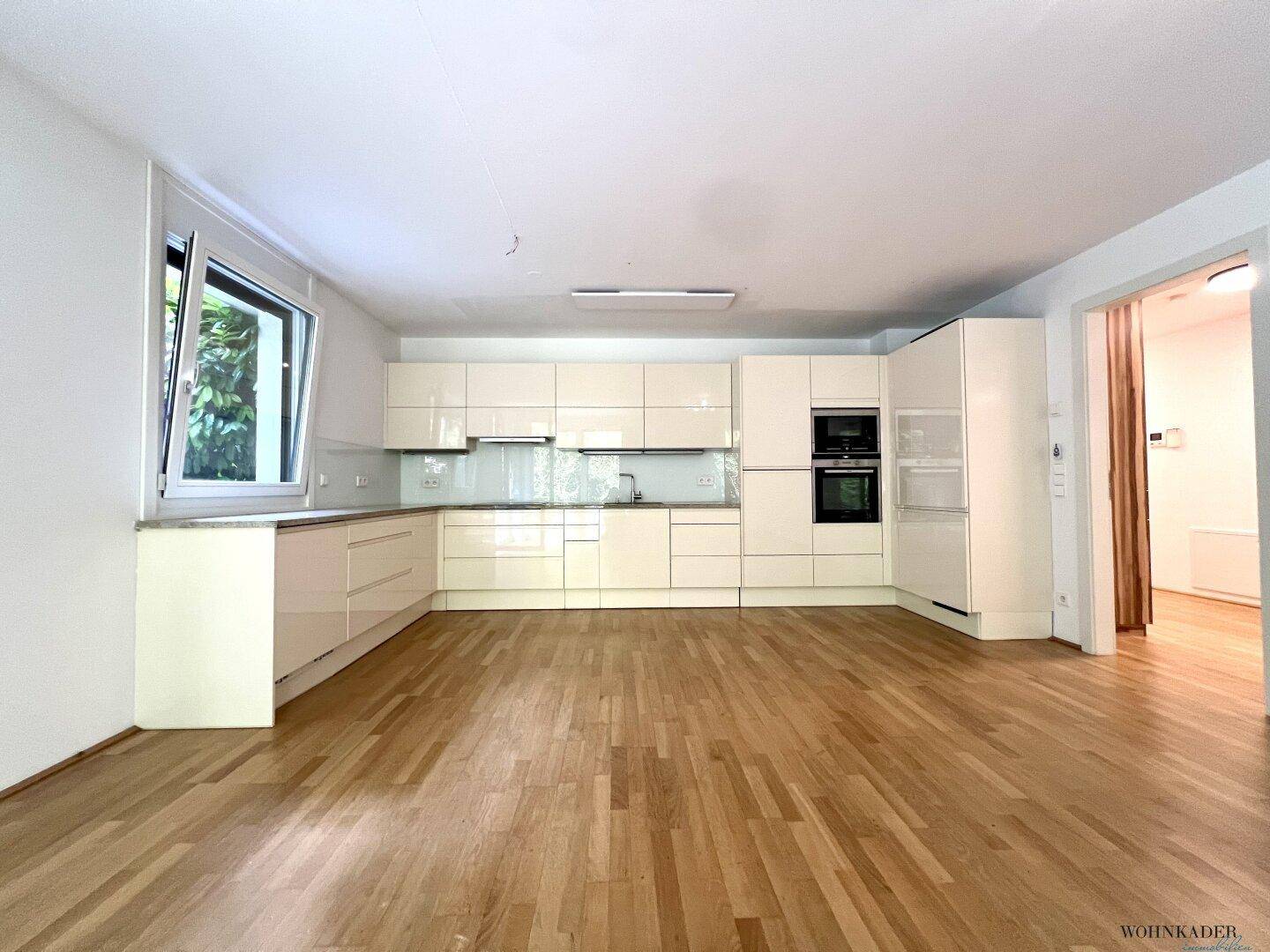 Helle Einbauküche mit Fenster, Granitarbeitsplatte und viel Stauraum in den Oberschränken.
